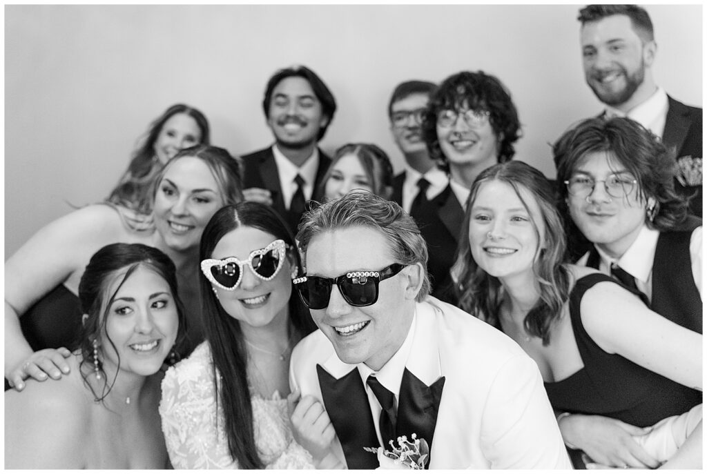 black and white image of couple wearing sunglasses and posing with their group of friends for this Wedding at The Rotunda at Lauxmont Farms
