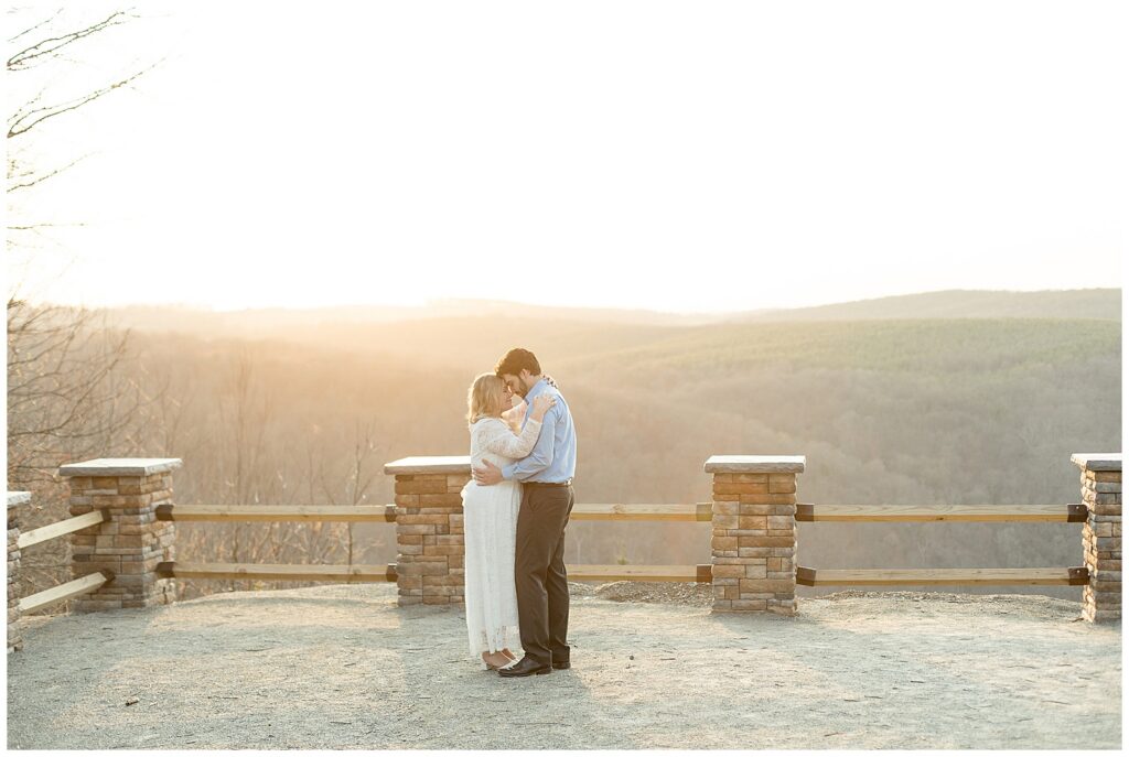 couple standing close with foreheads touching by fence at sunset for this Pinnacle Point Spring Engagement Session