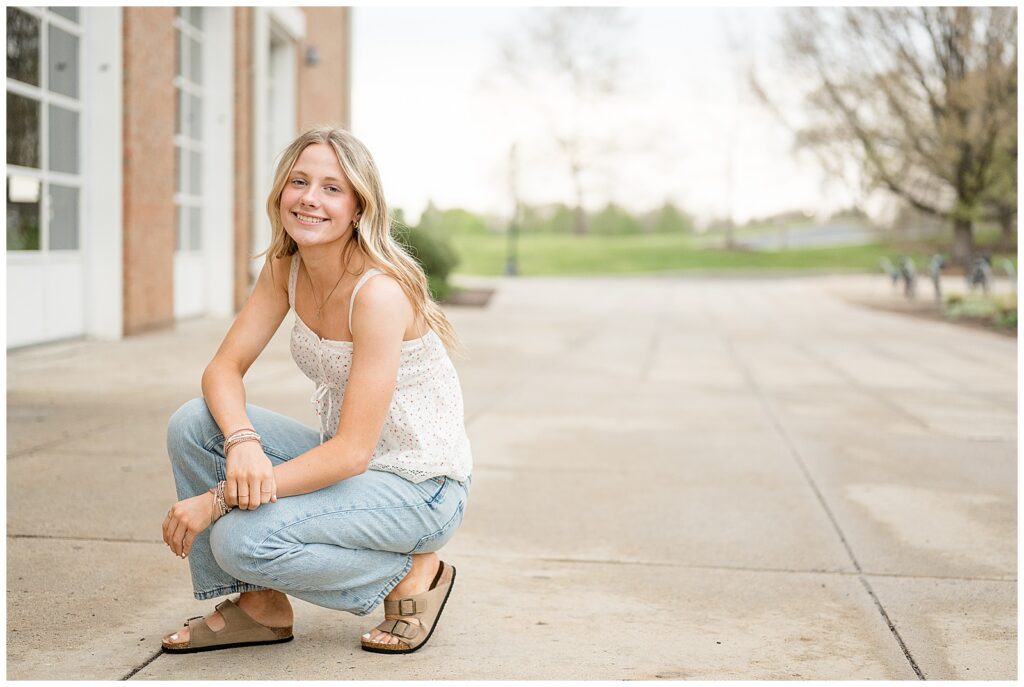 senior kneeling down in white shirt and light jeans