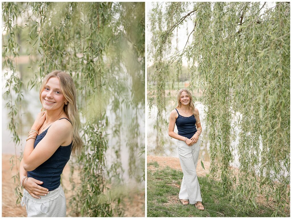 senior standing at willow tree in white linen pants and navy blue top