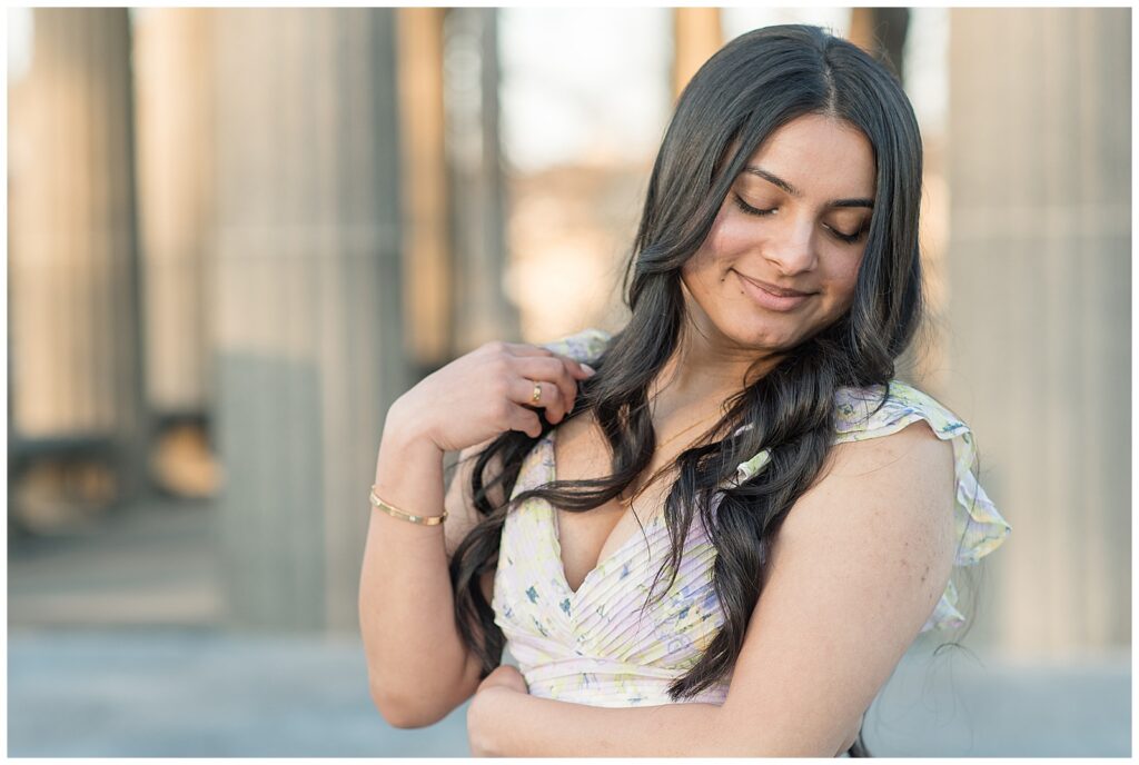 senior girl in long flowy dress looking down with columns behind her for this Spring Masonic Village Senior Session