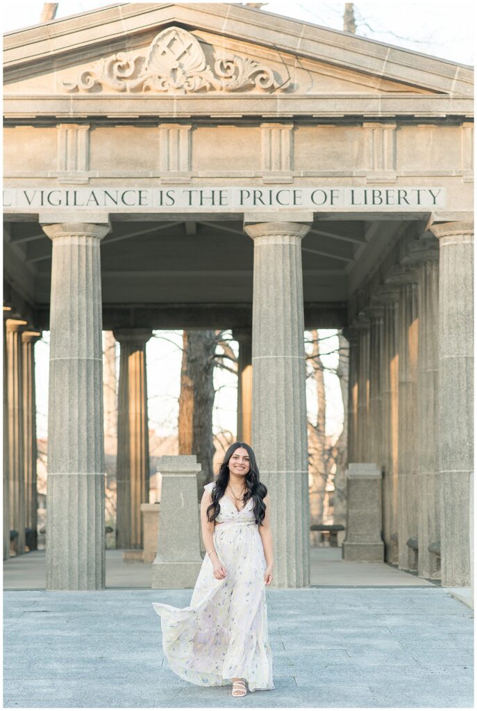 senior girl walking toward camera in front of concrete column structure for this Spring Masonic Village Senior Session