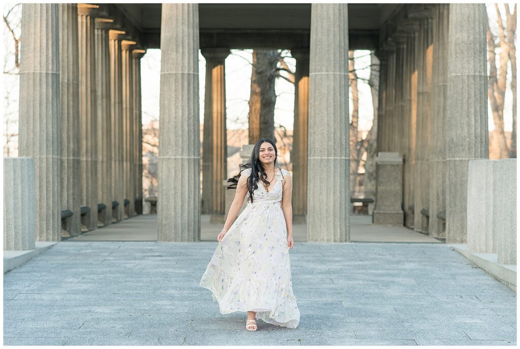 senior girl moving her long flowy dress in front of concrete columns for this Spring Masonic Village Senior Session