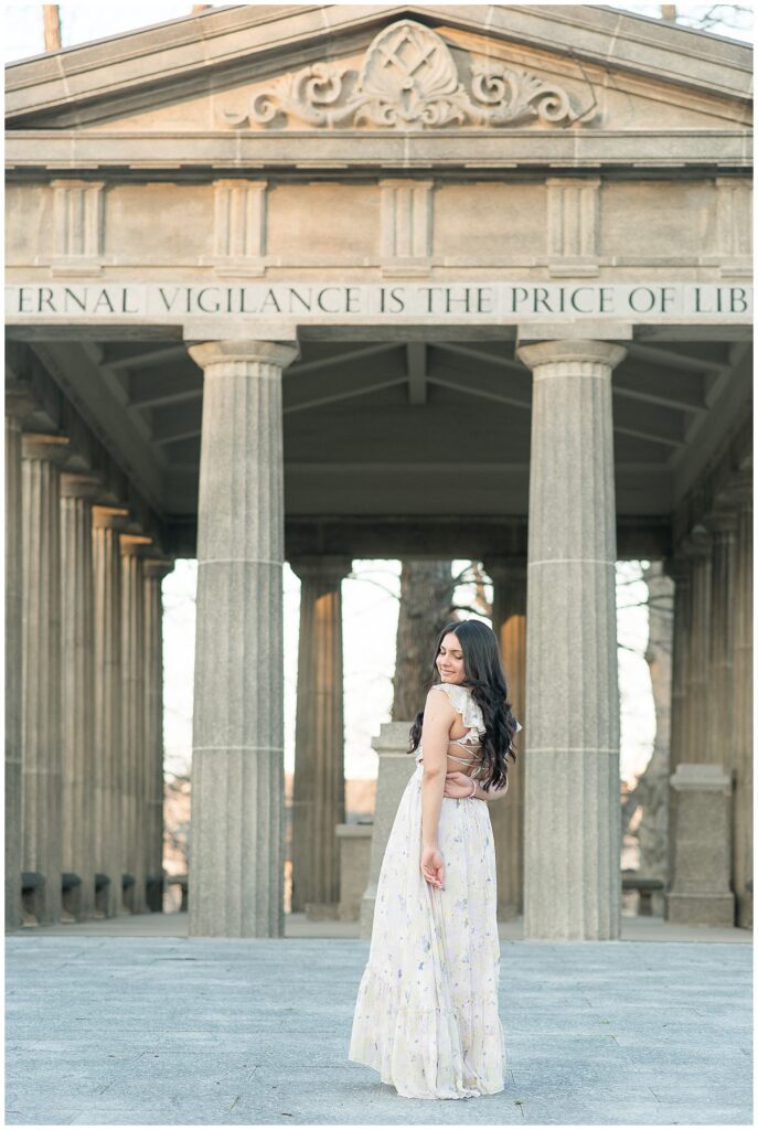 senior girl with back to camera looking back over her left shoulder by concrete structure for this Spring Masonic Village Senior Session