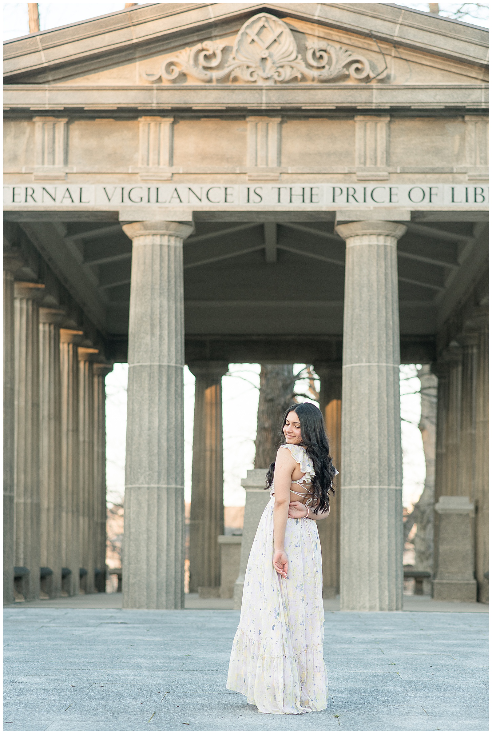 senior girl with back to camera looking back over her left shoulder by concrete structure for this Spring Masonic Village Senior Session