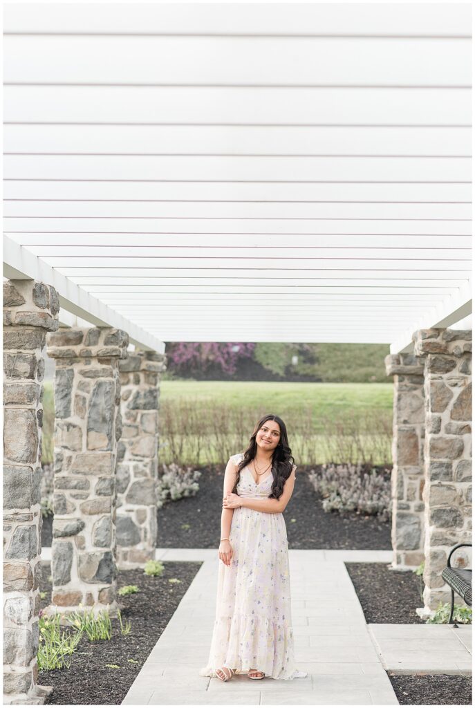 senior girl standing on pathway by stone columns for this Spring Masonic Village Senior Session