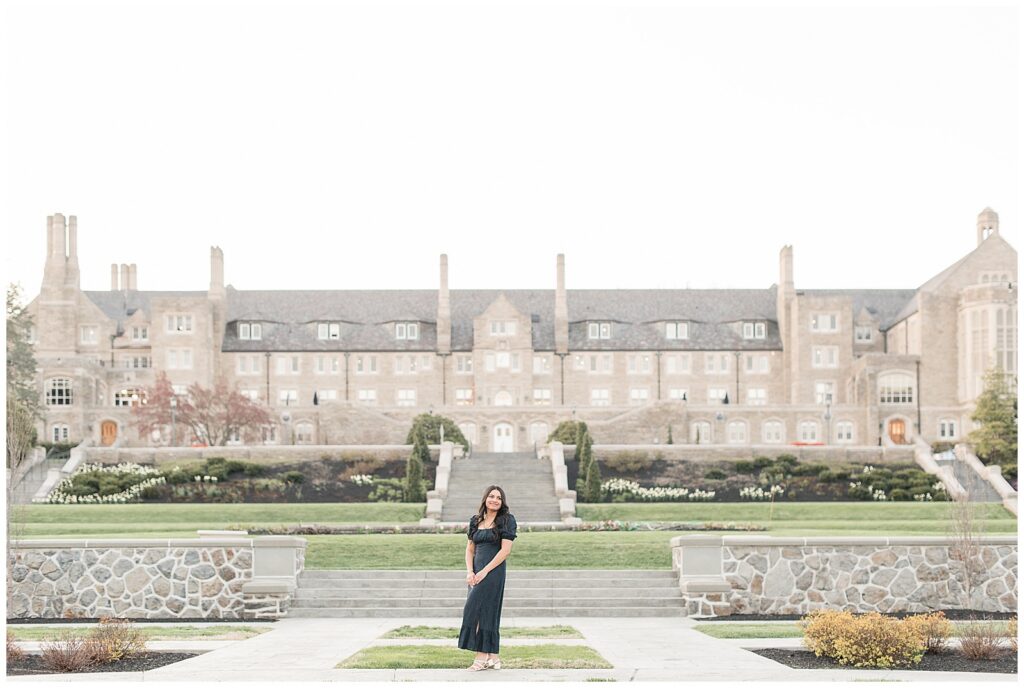 senior girl in long flowy black dress standing in front of majestic building for this Spring Masonic Village Senior Session