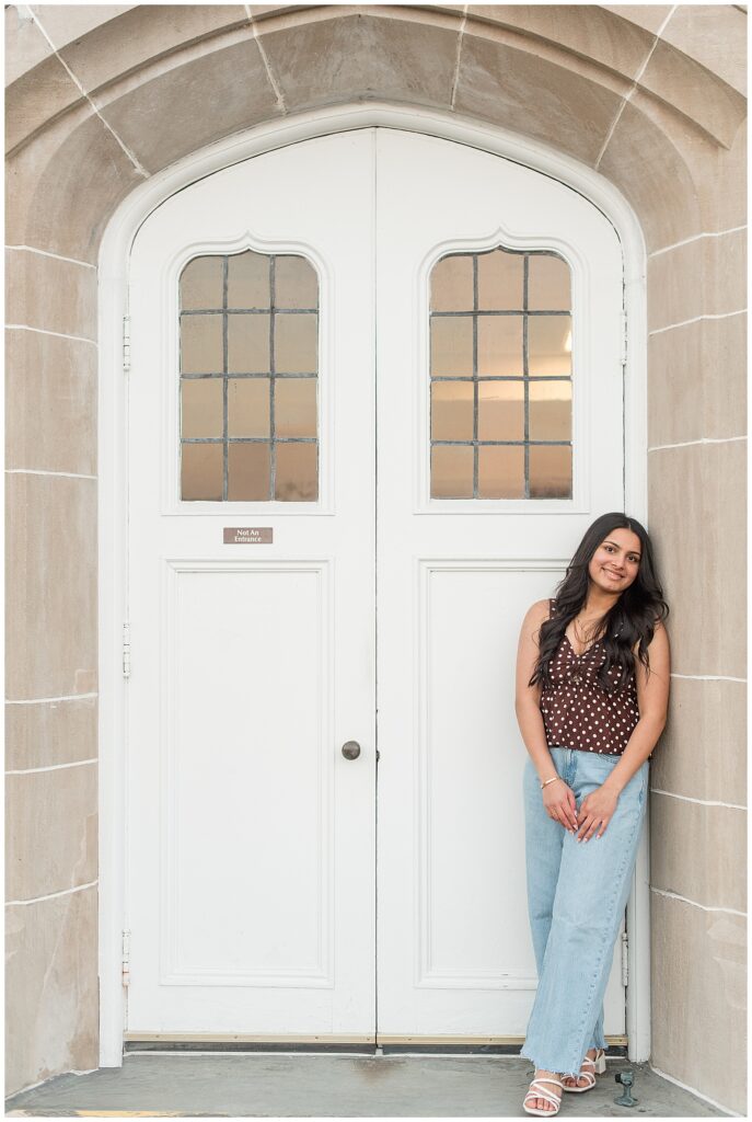 senior girl leaning against concrete wall by arched white doorway for this Spring Masonic Village Senior Session