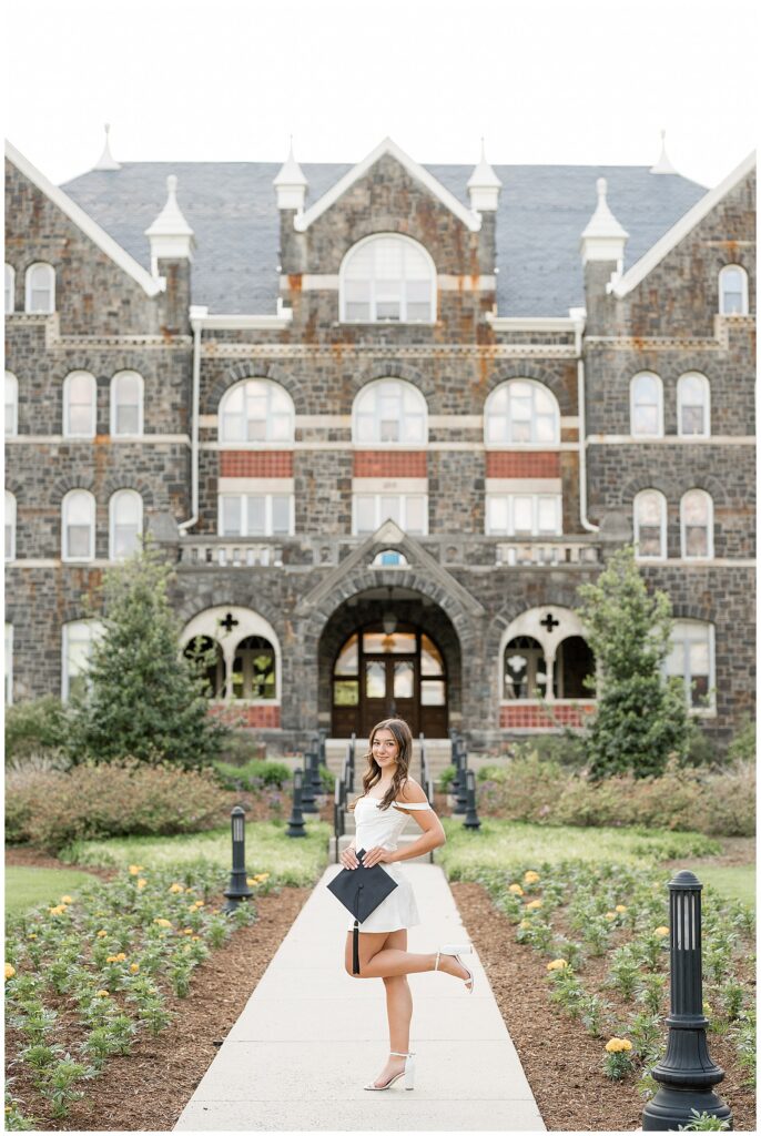 grad standing holding cap smiling at camera at Moravian University