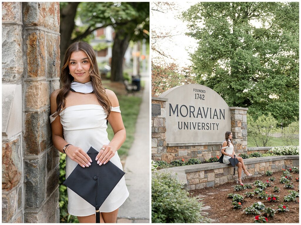 grad wearing white dress sitting at Moravian University sign