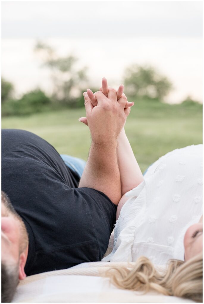 couple laying on backs holding hands up in air