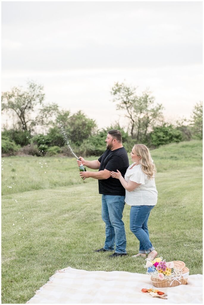 couple popping bottle of champagne during spring Overlook Park engagement session