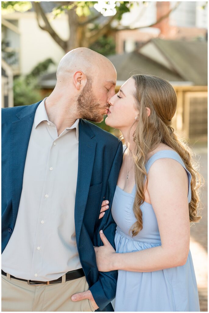 Close-up of engaged couple sharing a tender kiss on a sun-drenched brick street in downtown Lancaster PA, photographed by Lancaster engagement photographer Heather Marie Photography