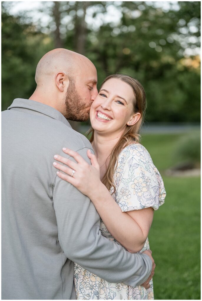 Close-up engagement portrait of woman laughing joyfully as her fiancé kisses her cheek at Lancaster County Central Park, summer engagement photographer Heather Marie Photography