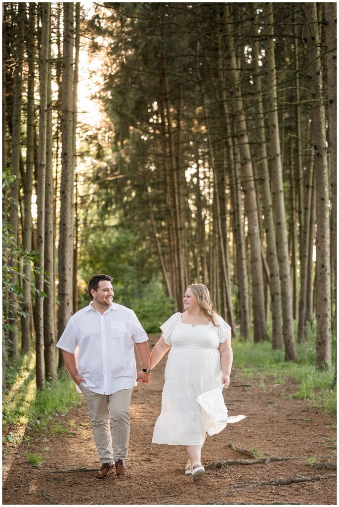 Engaged couple walking hand in hand through a pine tree grove at Overlook Park in Lancaster PA, romantic summer engagement photography by Heather Marie Photography