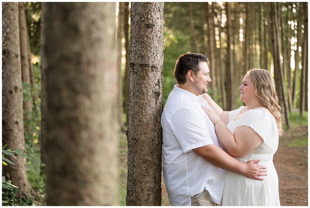 Engaged couple leaning against a pine tree and laughing together in the pine grove at Overlook Park Lancaster Pennsylvania, outdoor engagement portraits