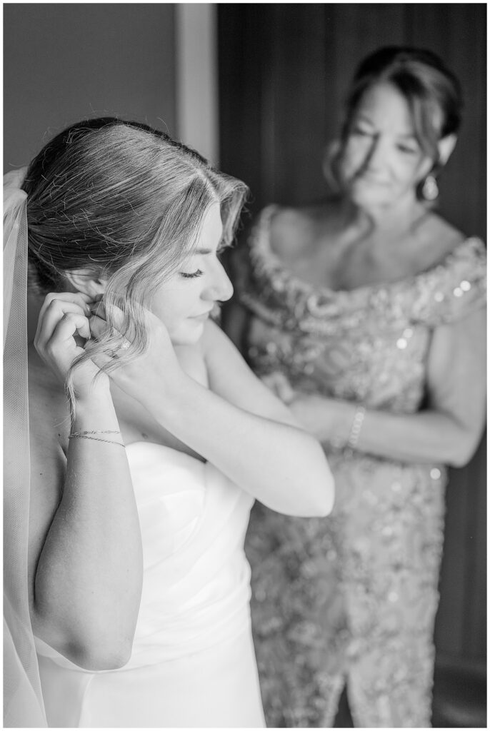 Black and white photo of mother of the bride helping her daughter put on her earrings on the wedding morning at Bluestone Estate | Heather Marie Photography