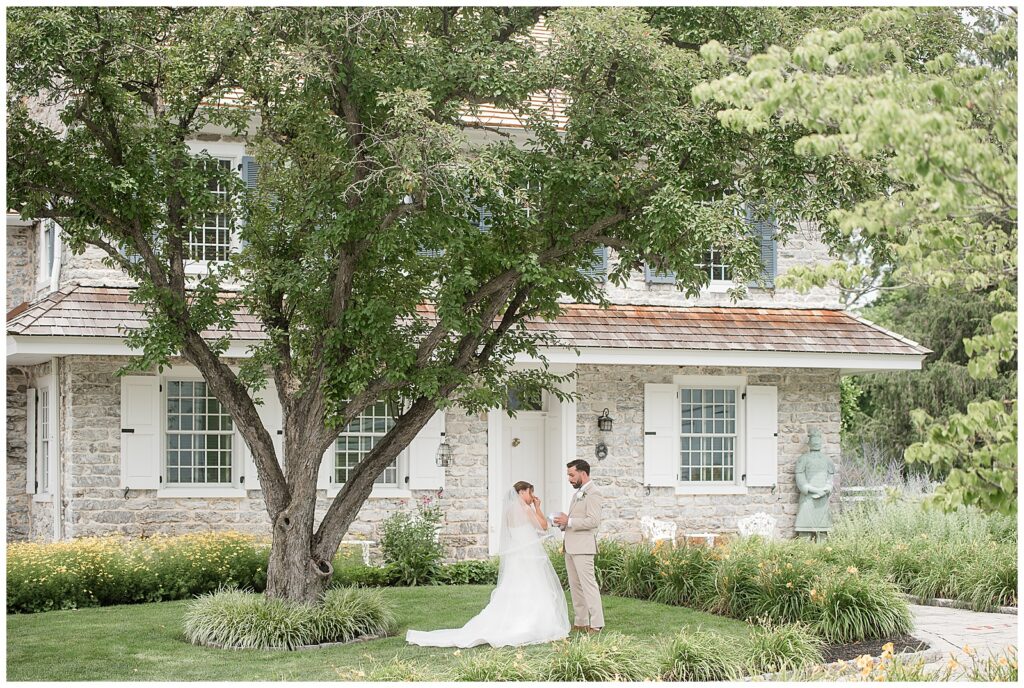 Wide panoramic view of bride and groom exchanging private vows during their first look with Bluestone Estate's stone building as the backdrop | Heather Marie Photography