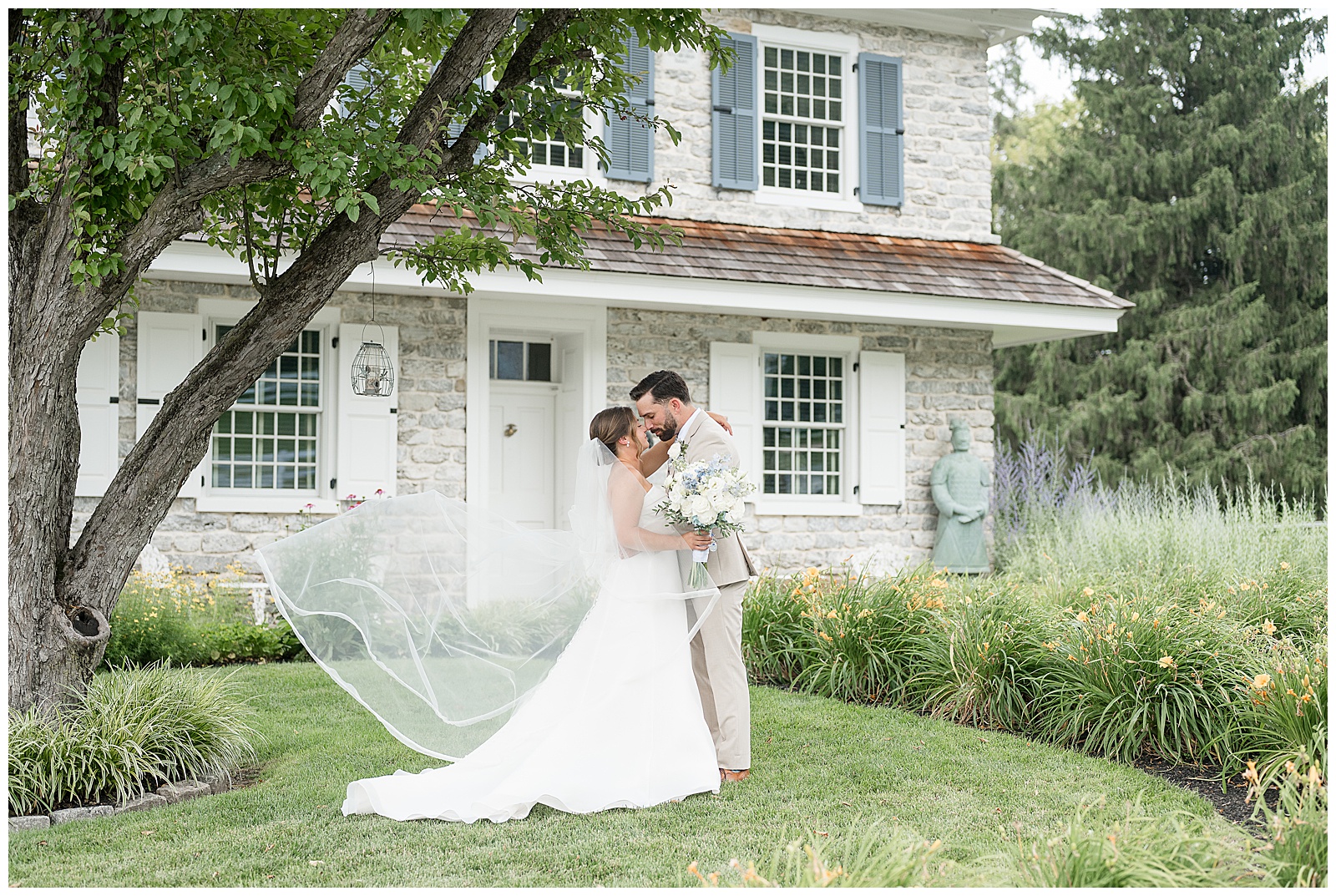 Bride and groom sharing a kiss with her cathedral veil blowing in the summer breeze during portraits at Bluestone Estate | Heather Marie Photography