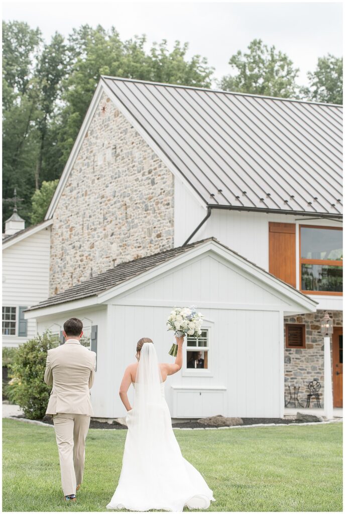 Bride raising her bouquet in celebration as she and her groom walk toward the Bluestone Estate barn as newlyweds | Heather Marie Photography