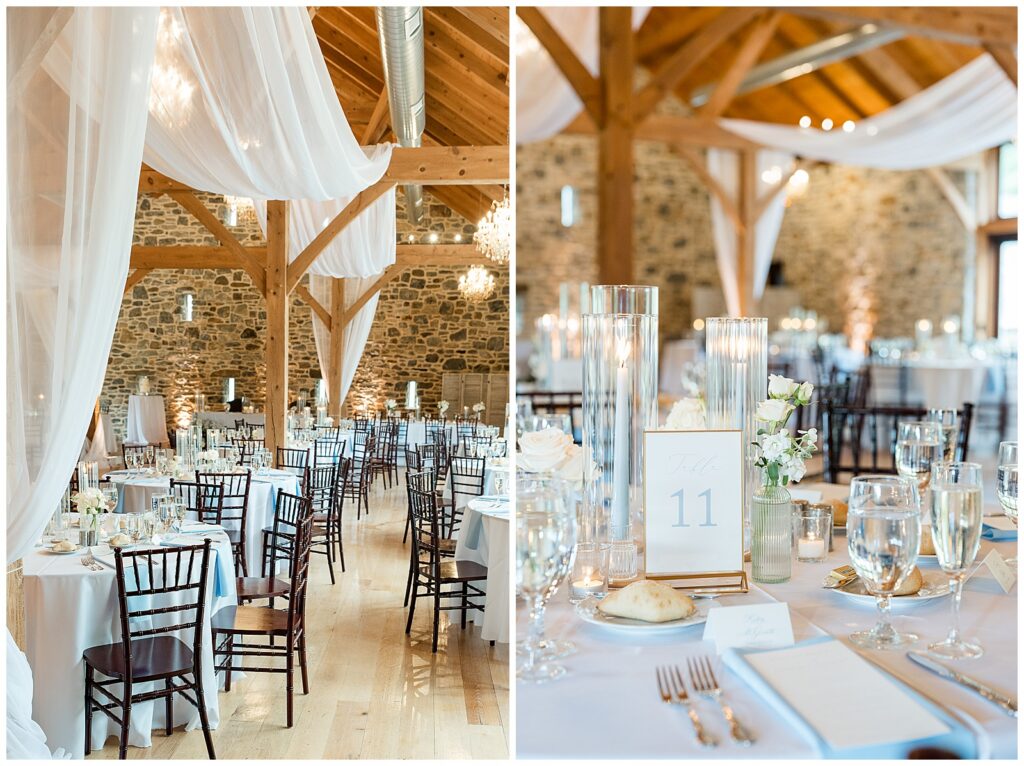 Bluestone Estate reception barn interior with exposed wood beams, white ceiling draping, crystal chandeliers, and dusty blue table linens | Heather Marie Photography // Reception table detail with tall glass candle cylinders, white florals, and a dusty blue table number at Bluestone Estate summer wedding | Heather Marie Photography