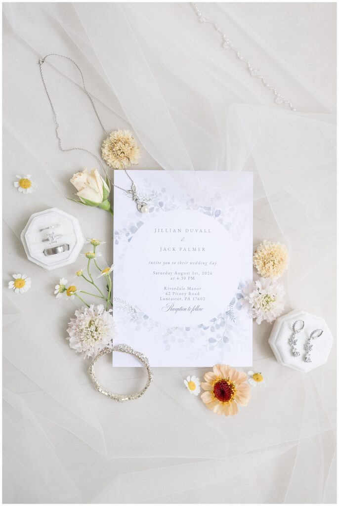 Wedding invitation suite for Jillian Duvall and Jack Palmer at Riverdale Manor with jewelry and florals flat lay