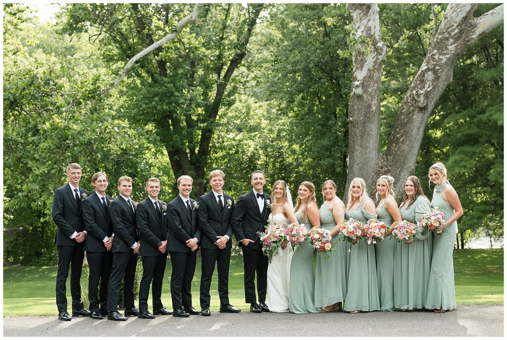 Full wedding party lineup portrait with groomsmen and bridesmaids holding colorful bouquets at Riverdale Manor Lancaster PA