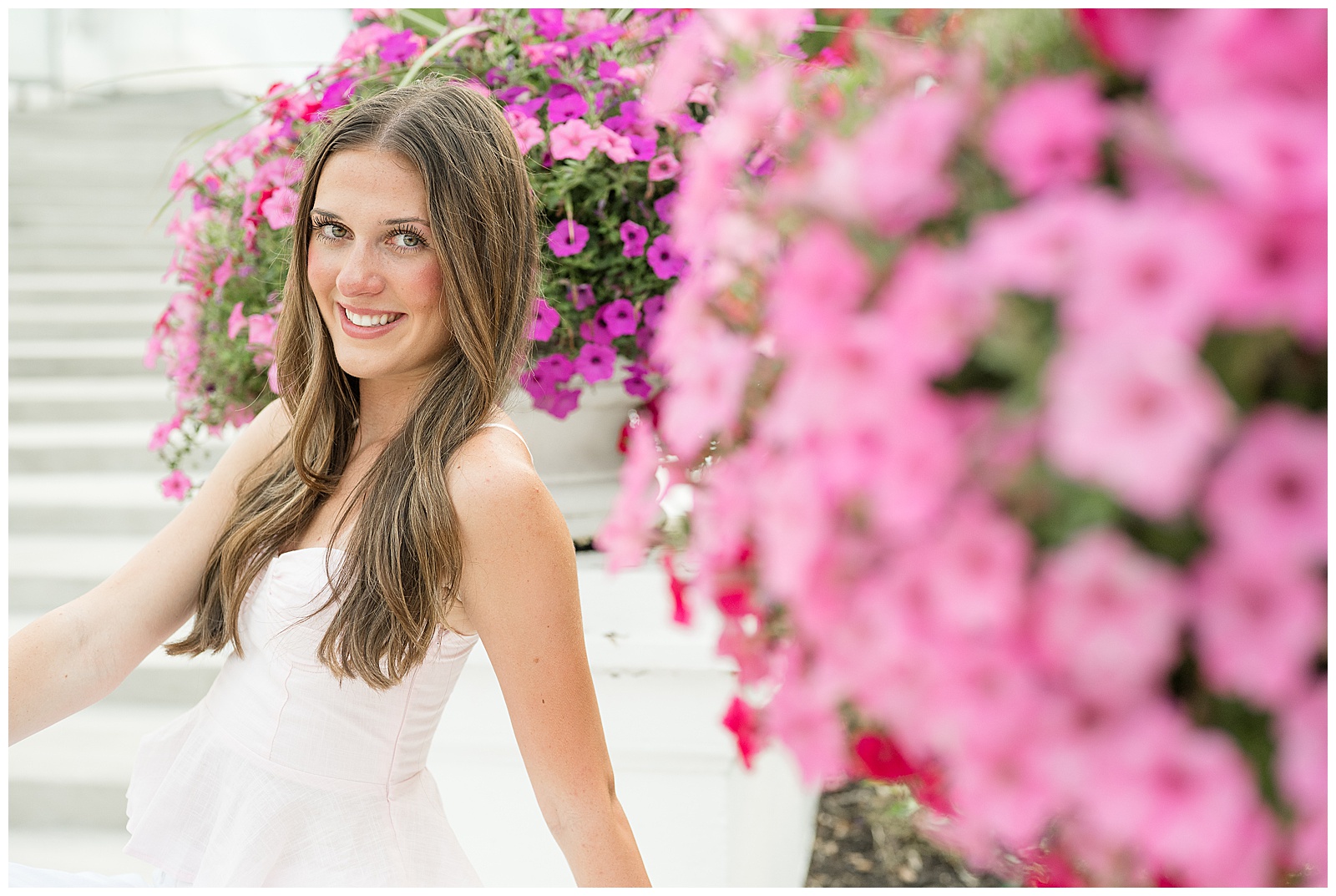 Close-up senior portrait with soft pink petunia flowers in the foreground at Hotel Hershey, Hershey PA senior photographer